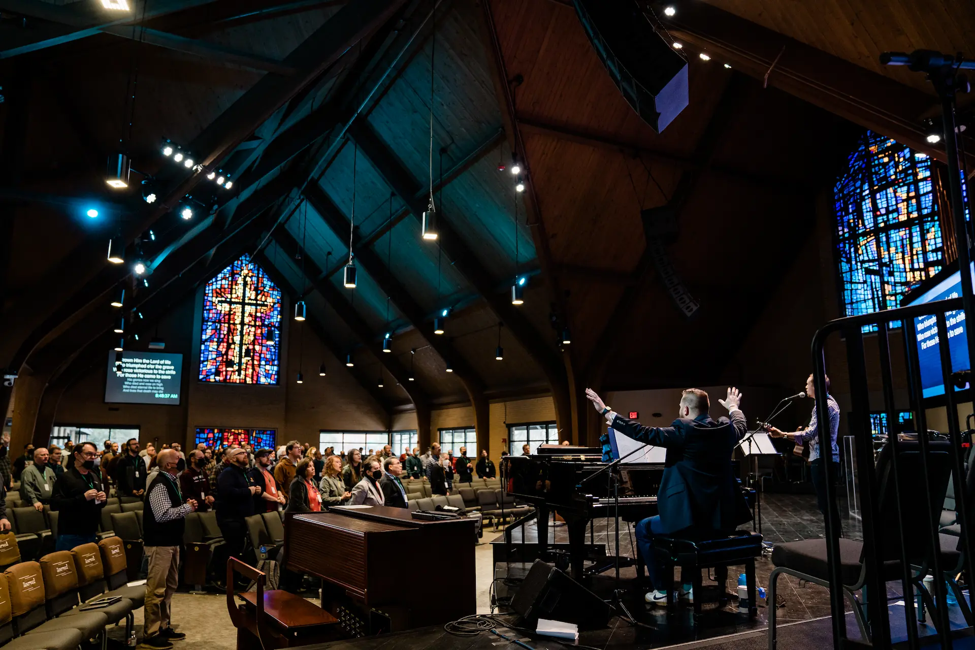 Congregational worship in a church with beautiful stained glass windows.